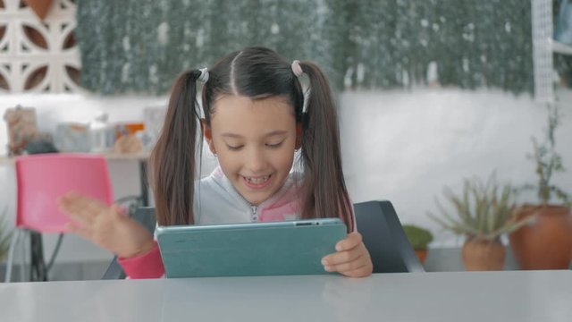 peque&ntilde;a joven con coletas en pijama saluda feliz por videoconferencia a su familia