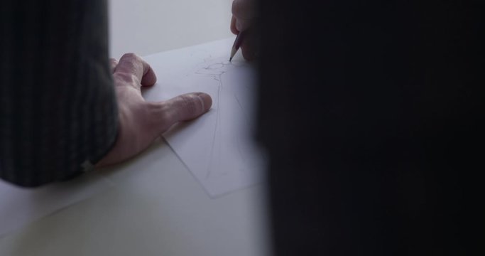 View of male designer's hand draws a sketch of the dress in the studio