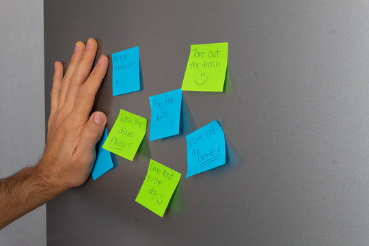 Reminders Taped To Fridge Door And Hand Holding To Read Them