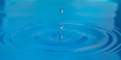 Gotas de agua color azul con morado suspendidas en el aire y  formando ondas en la superficie...