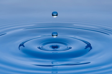 Gotas de agua color azul con morado suspendidas en el aire y  formando ondas en la superficie...
