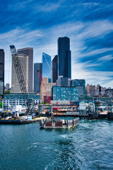 Obraz premium 2020-04-23 THE OLD AND NEW COLEMAN DOCK IN DOWNTOWN SEATTLE WITH THE CITY SKYLINE AND A BRIGHT BLUE SKY