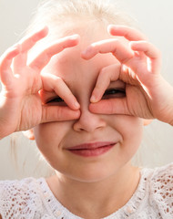 The girl covered her face with her hands. The child looks through his fingers.