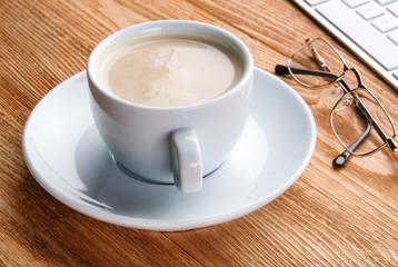 Cup of coffee and a computer on a wooden table. Desktop of a businessman. Work at home. Work with pleasure.