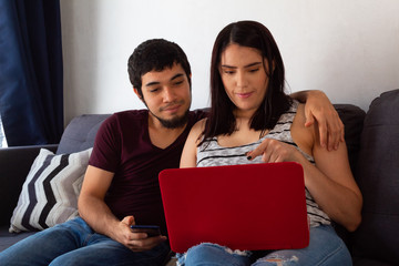 Hispanic couple using laptop on a sofa