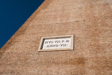brick wall with inscriptions in  square on a white background against blue sky roma italia coliseum