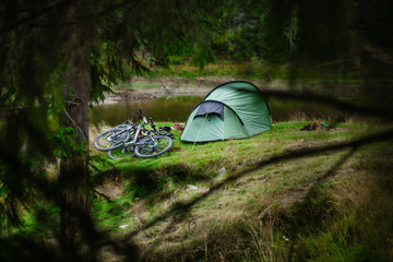 Mountain bikes near a tent in a camping spot on a hill with green grass. Beautiful places for...
