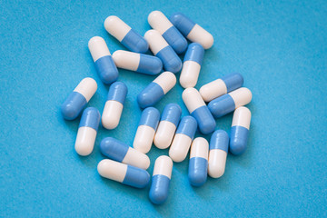 Lekarstwa, pigułki biało- niebieskie na niebieskim tle.