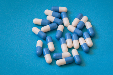 Lekarstwa, pigułki biało- niebieskie na niebieskim tle.