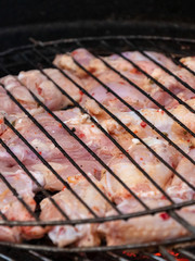 Grilled chicken legs on the flaming barbeque grill.