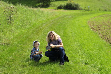 Mother and son sitting in the green meadow in the sun