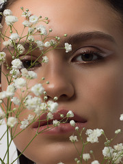 Close up portrait of a face with beautiful skin and nude makeup, eyeliner and long eyelashes, puffy...