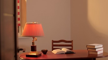Interior. Antique wooden table. There is an old lamp on the table, a pile of books, an open book....