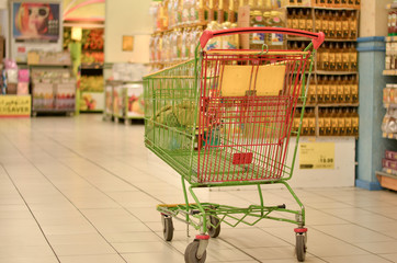 Shopping carts in a modern hypermarket store in a mall. The POS impulse products are clearly visible as people/customers are seen moving in FMCG area of the retail store - obrazy, fototapety, plakaty