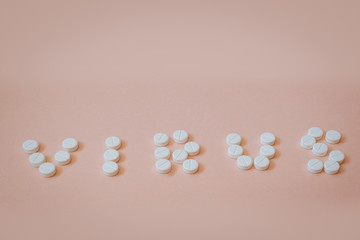 Białe tabletki ułożone w napis wirus.