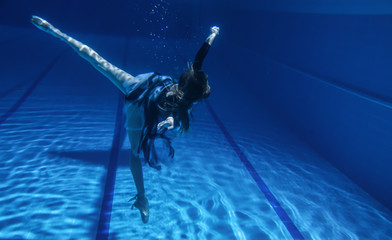 Ballerina jumps into the pool, slender professional dancer under the water and above the surface of the water, frozen movement dancing under the water in Pointe shoes