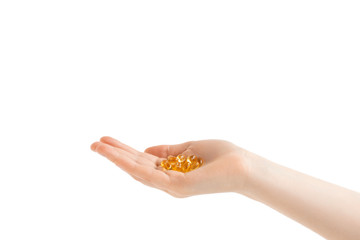 Fish oil golden capsules in woman hands. Isolated on white background.