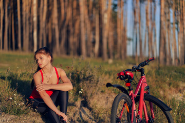 Naklejka na ściany i meble Girl athlete with a bicycle resting on nature at the edge of the forest.