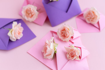 Purple and pink paper open envelopes with full small rose flowers on color background. Spring, summer concept. Romance, love notes, greeting card for March 8 International Woman's, Valentine's day
