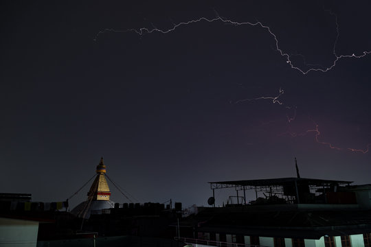 A thunderstorm front rages over the city of Kathmandu, in the place where Boudha Stupa is located. Lightning discharge and a stupa without night illumination are visible.