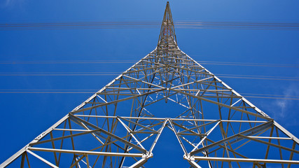 High voltage electrical tower. Electric poles in front of blue sky.