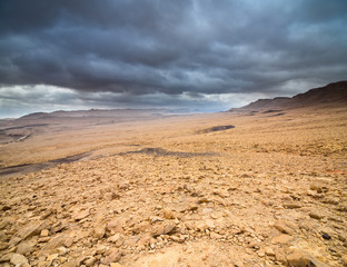Deserted rocky landscape under the dramatic cloudy sky, wide angle.