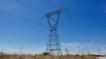 High voltage electrical tower. Electric poles in front of blue sky.