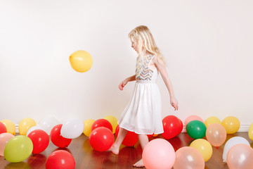 Fototapeta na wymiar Cute adorable little girl celebrating birthday at home. Lovely girl child with colorful balloons having fun. Quarantine birthday party at home alone during a COVID-19 pandemic self isolation.