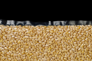 part of pine nuts packed in vacuum bag, black background