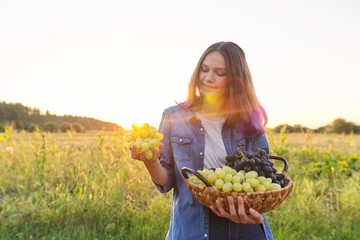 Beautiful teenager girl with basket with crop of green and blue grapes