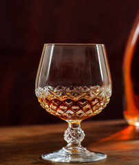 Crystal glass of cognac, brandy on a wooden bar counter