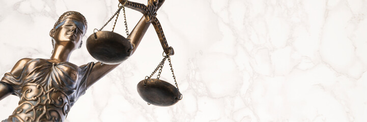 Bronze Themis statue - symbol of Justice - viewed from a low angle with a marble background © Wes