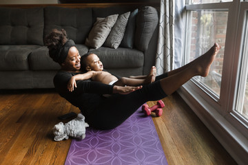 Smiling woman exercising with her son at home during quarantine
