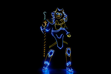 Obraz na płótnie Canvas A man in the neon costume of Pharaoh is dancing in the dark