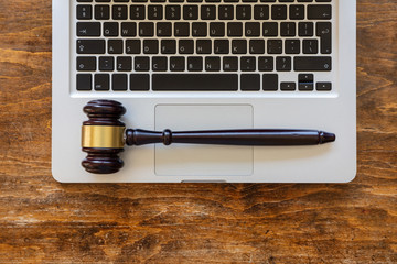 Judge gavel on a laptop, wooden background, top view. Online auction concept - obrazy, fototapety, plakaty