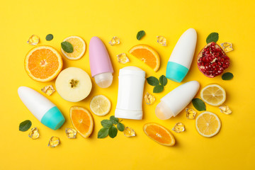 Body deodorants, ice and fruits on yellow background, blank space for text