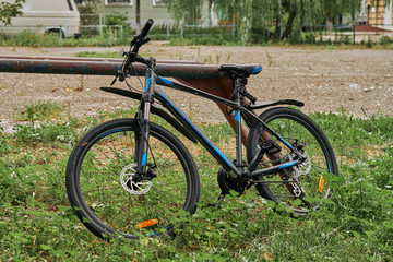 Fototapeta premium the bike is locked near an iron pillar in the yard.