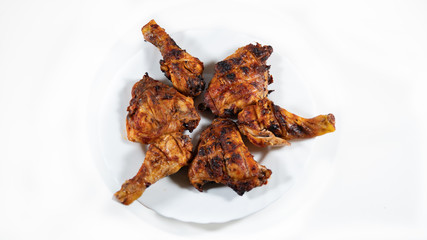 Chicken legs marinated in spices, grilled, arranged in a white plate, on a white background