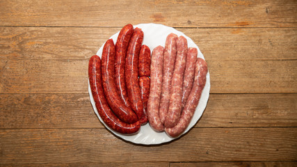 
Sausages and merguez arranged in a white plate, on a woody background
