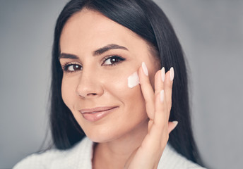 Serene girl using a moisturizing skincare product