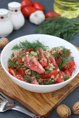Fresh tomato salad with garlic, dill and nut dressing in a white bowl on wooden board, selective focus, Healthy Eating Day, Vertical format