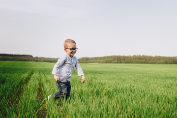 Family in nature. Picnic in the forest, in the meadow. Blue clothes. The boy in glasses with blond hair. Joy. Runs through the green grass.