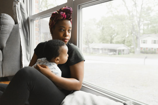 Mother and toddler looking out window at home