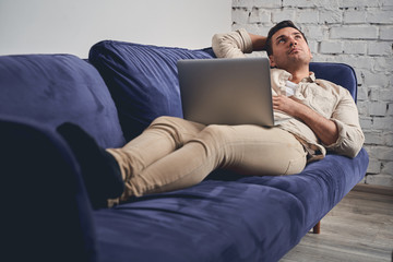 Pensive short-haired man resting on the sofa