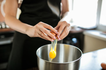 Obraz na płótnie Canvas Confectioner breaks an egg into a mixer bowl 
