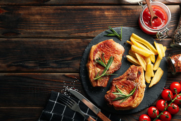 Composition with fried steaks on wooden background. Grilled food