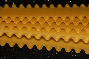 Pasta on a black shiny background. Lasagna sheets on a dark background. Food frame.