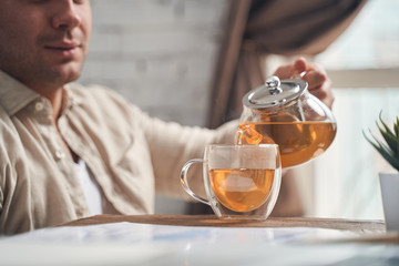 Focused male holding a teapot infuser in his hand