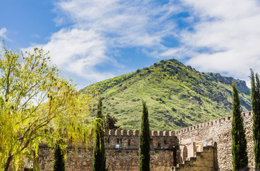 Fototapeta na wymiar Panoramic view of the Caucasus mountains, with the Svetitskhoveli Cathedral external wall in the foreground. Located in Mtskheta village, near Tbilisi, Georgia...Y