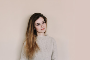 Young pretty woman on beige background. Portrait of a pretty smiling brunette with long hair, makeup. Relaxed young woman. 